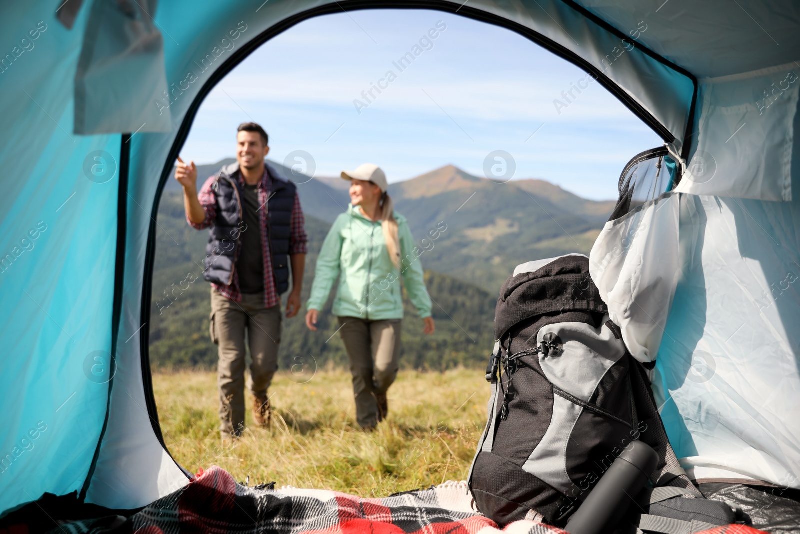 Photo of Couple in mountains on sunny day, view from camping tent