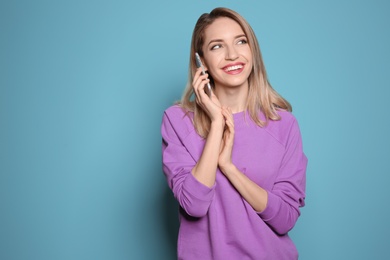 Young woman talking on phone against color background