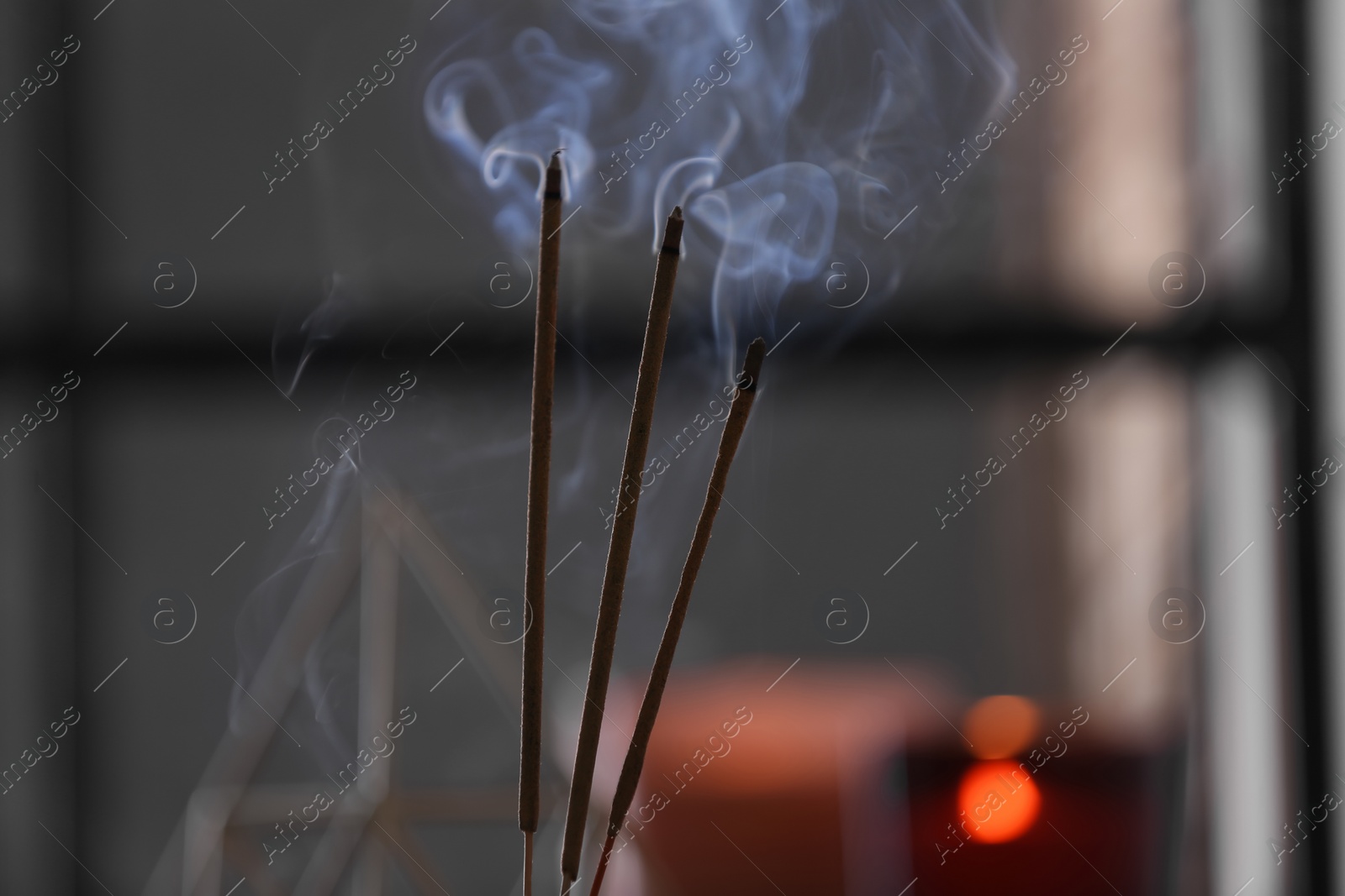 Photo of Incense sticks smoldering on blurred background, closeup