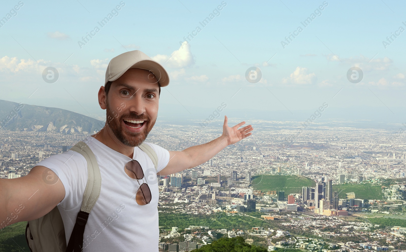 Image of Smiling man taking selfie against valley with city in mountains