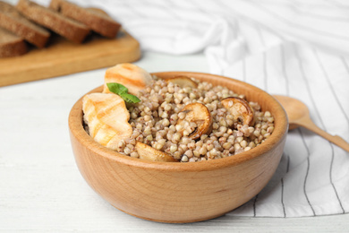 Photo of Tasty buckwheat porridge with meat on white wooden table