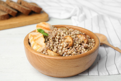 Tasty buckwheat porridge with meat on white wooden table