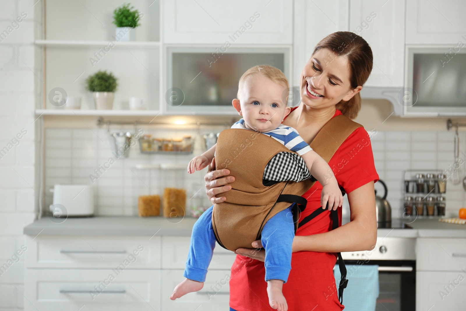 Photo of Woman with her son in baby carrier at home. Space for text