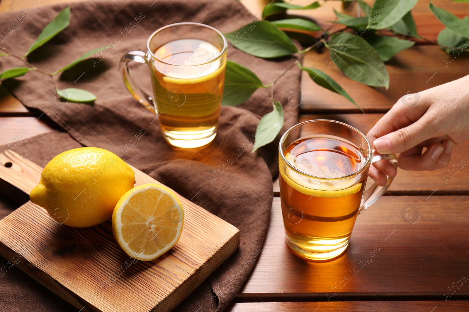 Photo of Woman with cup of fresh iced tea at wooden table, closeup