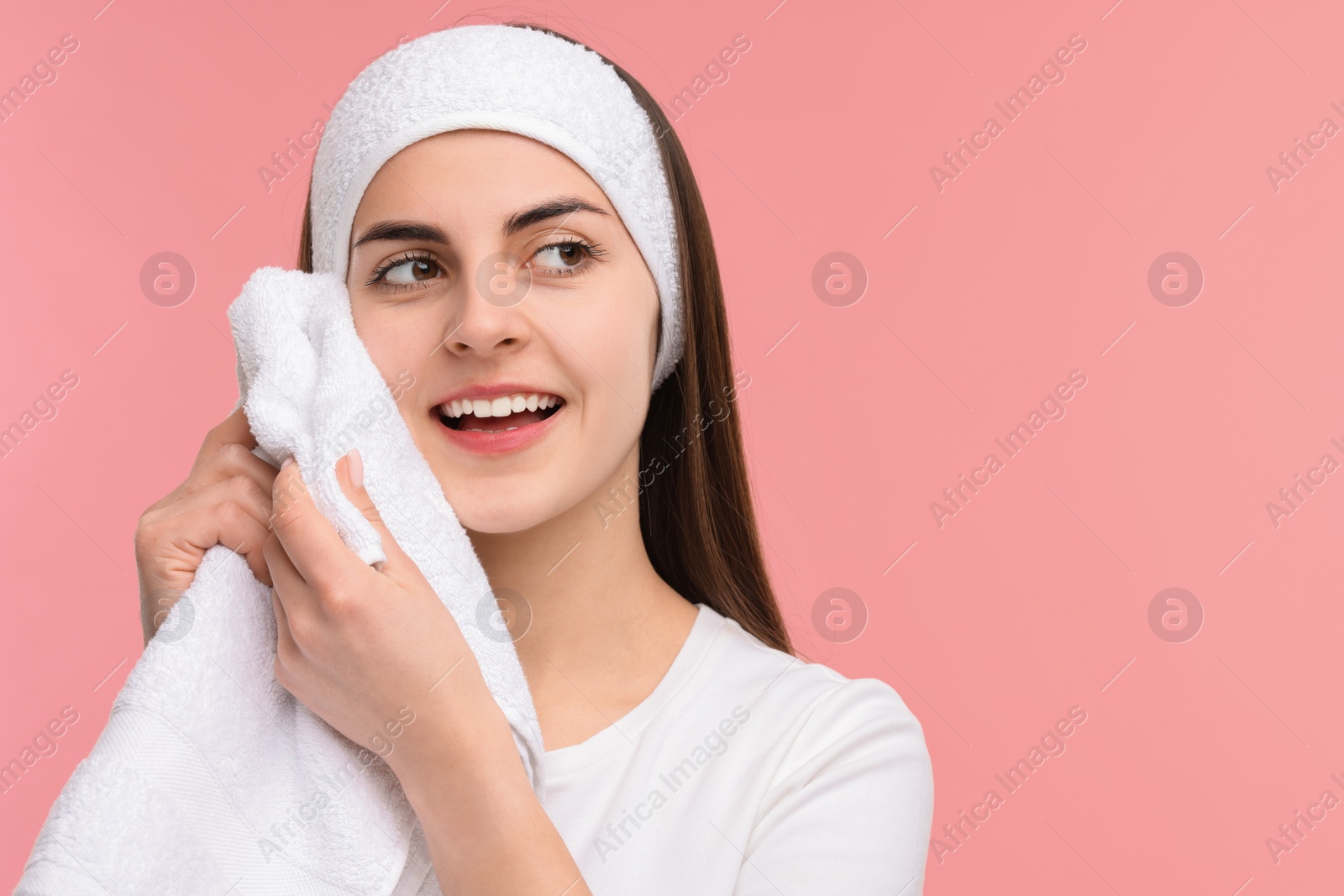 Photo of Washing face. Young woman with headband and towel on pink background, space for text