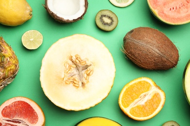 Photo of Flat lay composition with tasty melon and fresh tropical fruits on green background