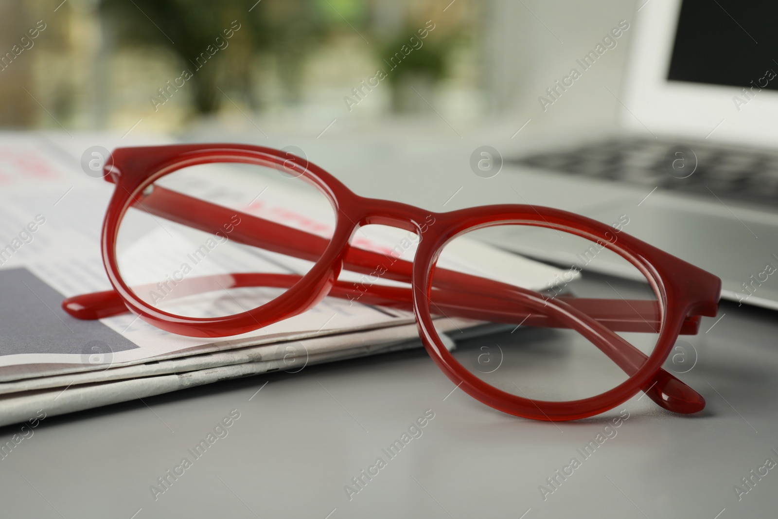 Photo of Newspaper and glasses on grey table, closeup