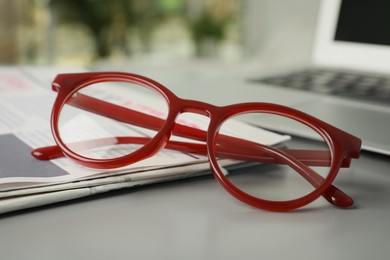 Photo of Newspaper and glasses on grey table, closeup