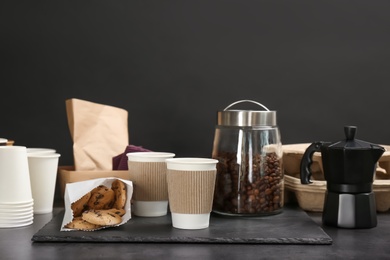 Composition with aromatic hot coffee in paper cups and cookies on table