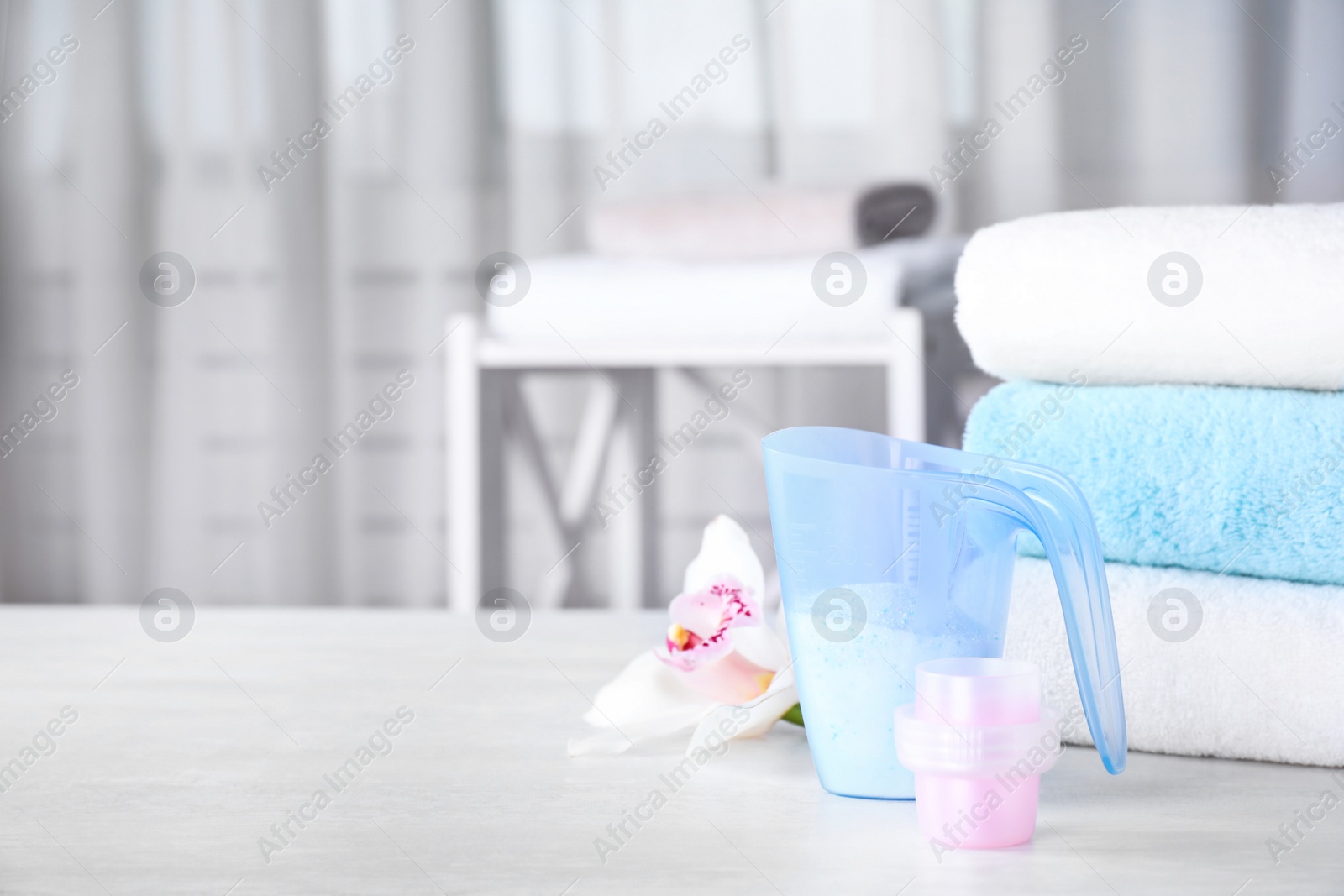 Photo of Composition with clean towels and laundry detergents on table against blurred background. Space for text