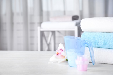 Photo of Composition with clean towels and laundry detergents on table against blurred background. Space for text