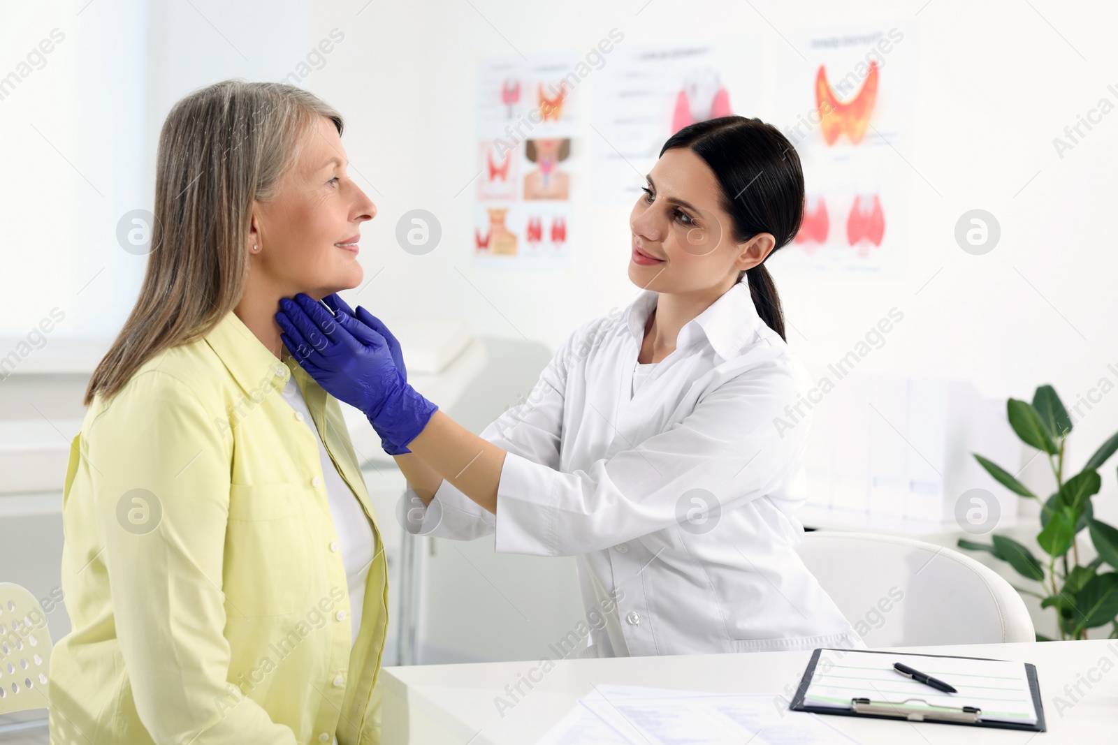 Photo of Endocrinologist examining thyroid gland of patient at table in hospital