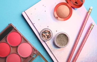 Flat lay composition with coral cosmetics and notebook on light blue background