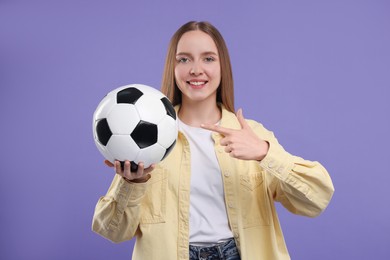 Photo of Happy sports fan with ball on purple background