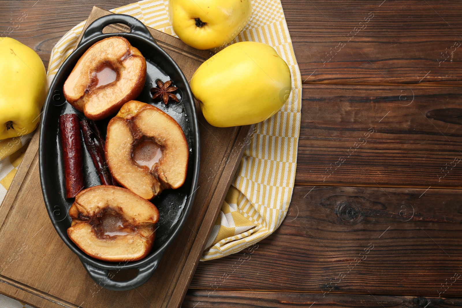 Photo of Tasty baked quinces with spices and honey in dish on wooden table, flat lay. Space for text