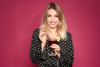 Beautiful young woman with glass of martini cocktail on color background