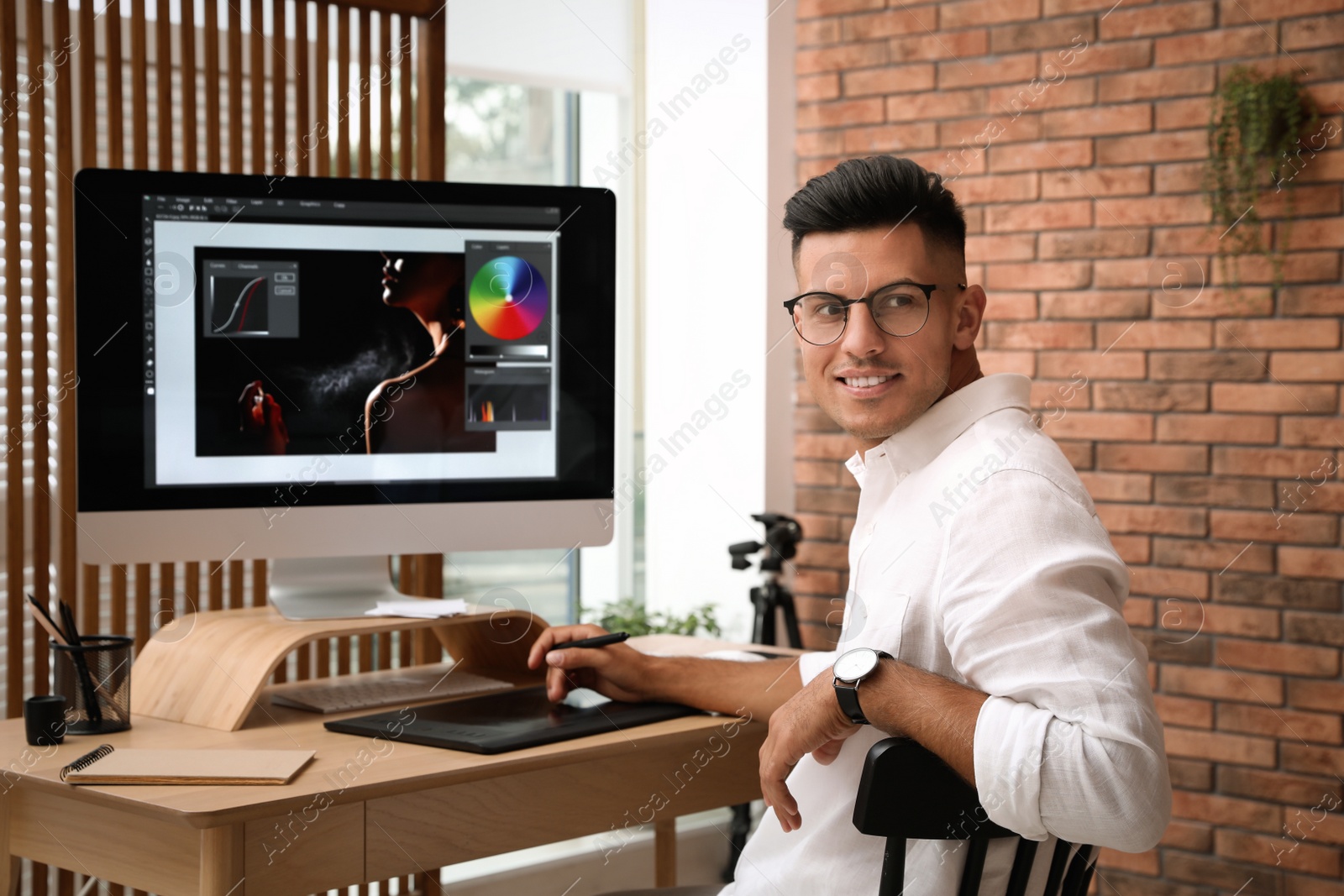 Photo of Professional retoucher working on graphic tablet at desk in office