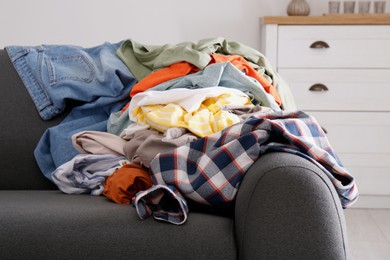 Photo of Messy pile of dirty clothes on sofa in living room. Tidying up method