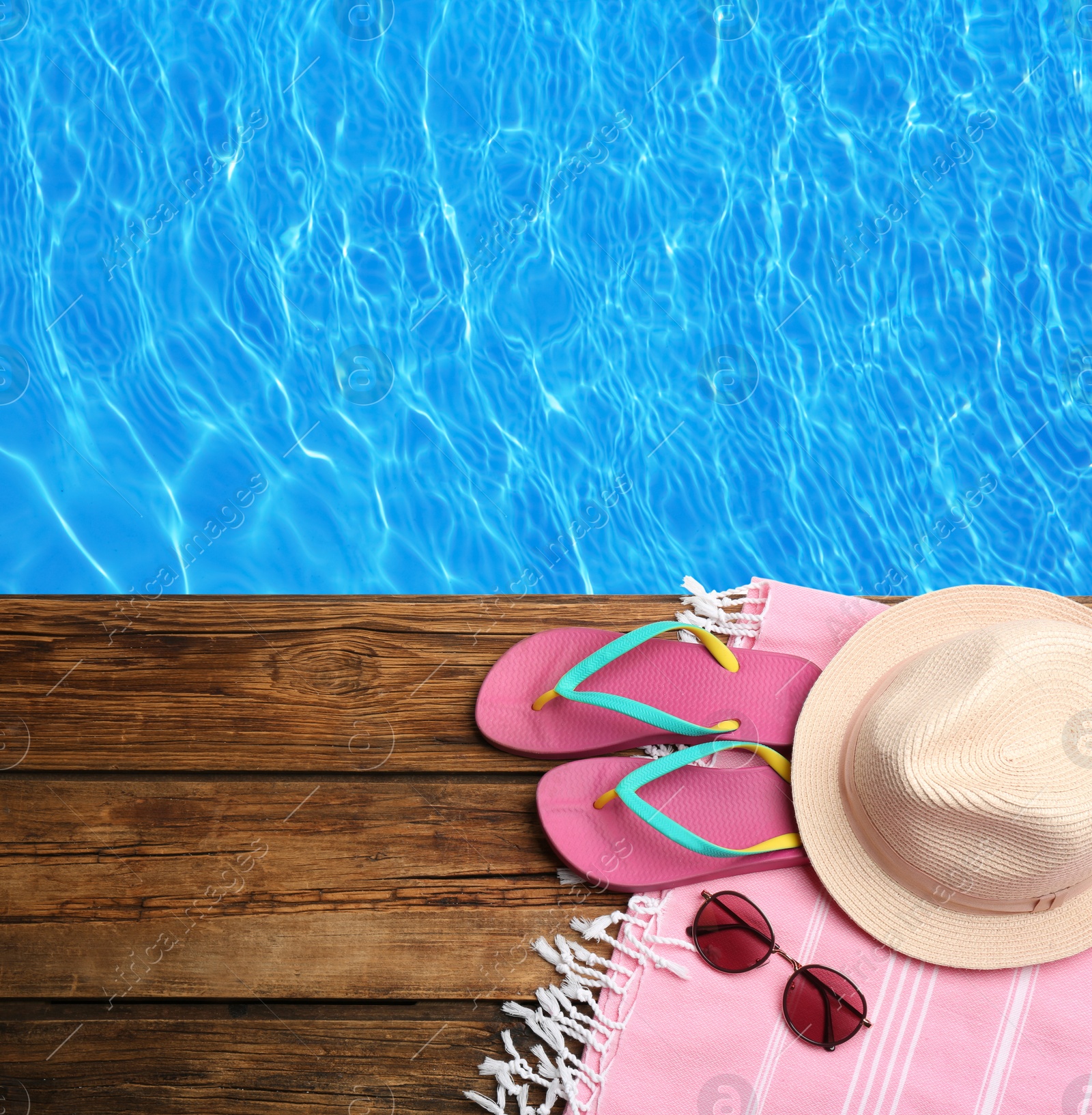 Image of Beach accessories on wooden deck near swimming pool, flat lay. Space for text 