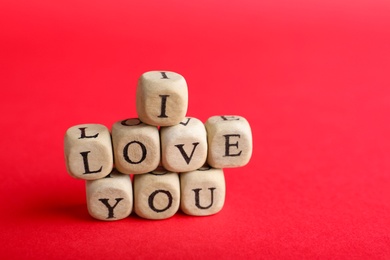 Photo of Cubes with words I Love You on red background. Space for text