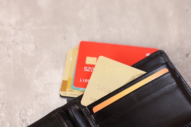 Many different credit cards and leather wallet on grey table, closeup