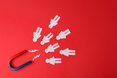 Photo of Magnet and paper people on red background, flat lay