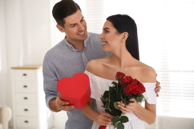 Photo of Man presenting gift to his beloved woman at home. Valentine's day celebration