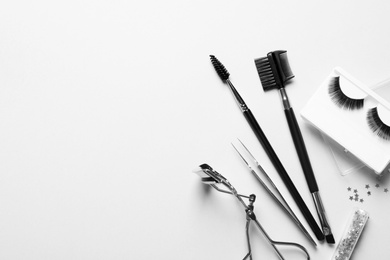 Photo of Composition with false eyelashes and tools on white background, top view