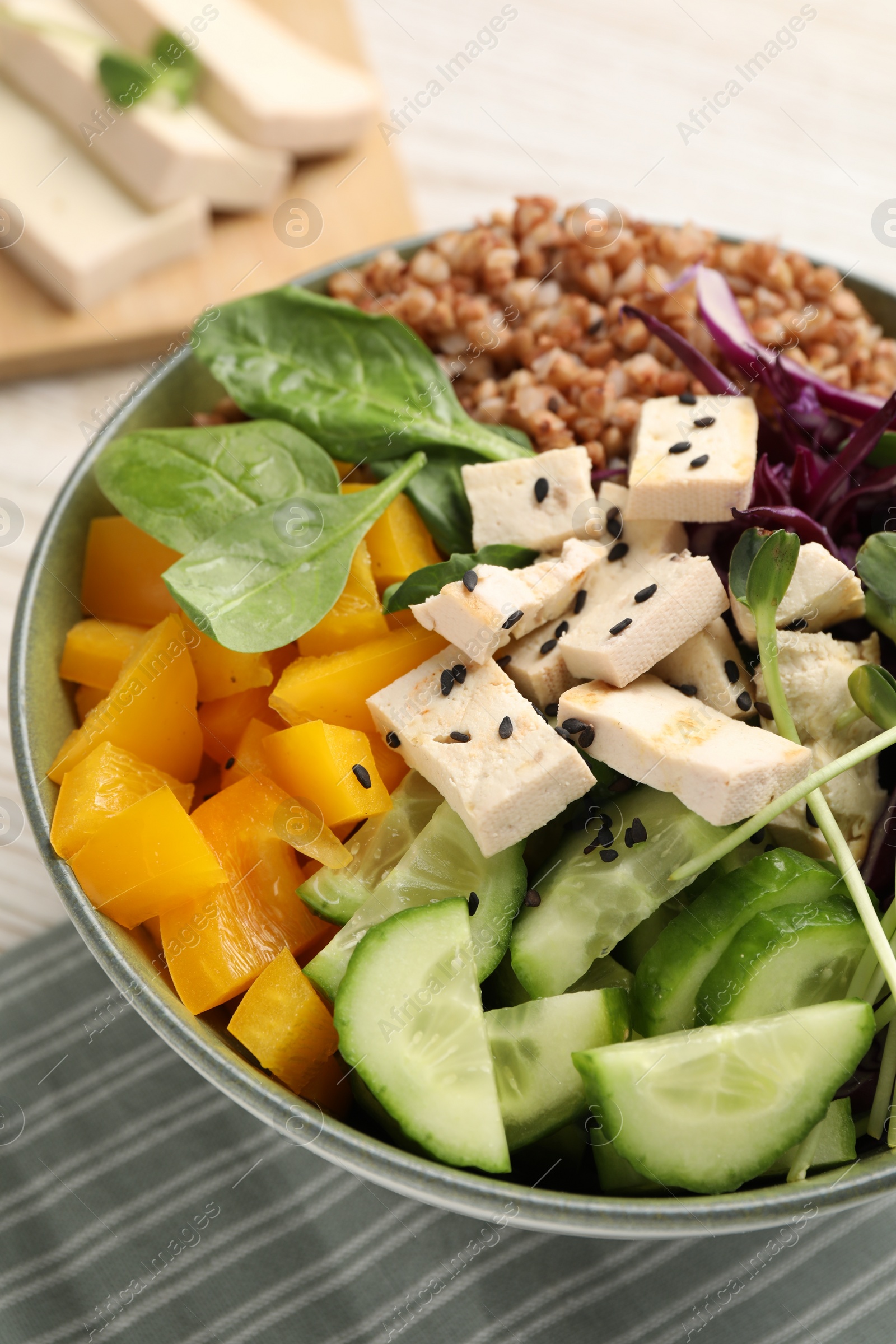 Photo of Delicious vegan bowl with bell pepper, tofu and cucumbers on table, closeup