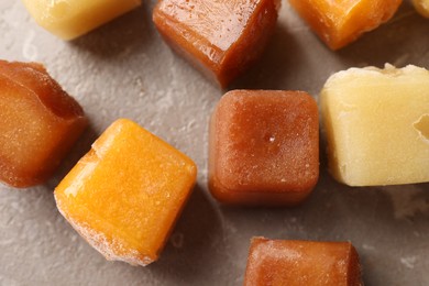 Photo of Different frozen fruit puree cubes on brown marble table, flat lay