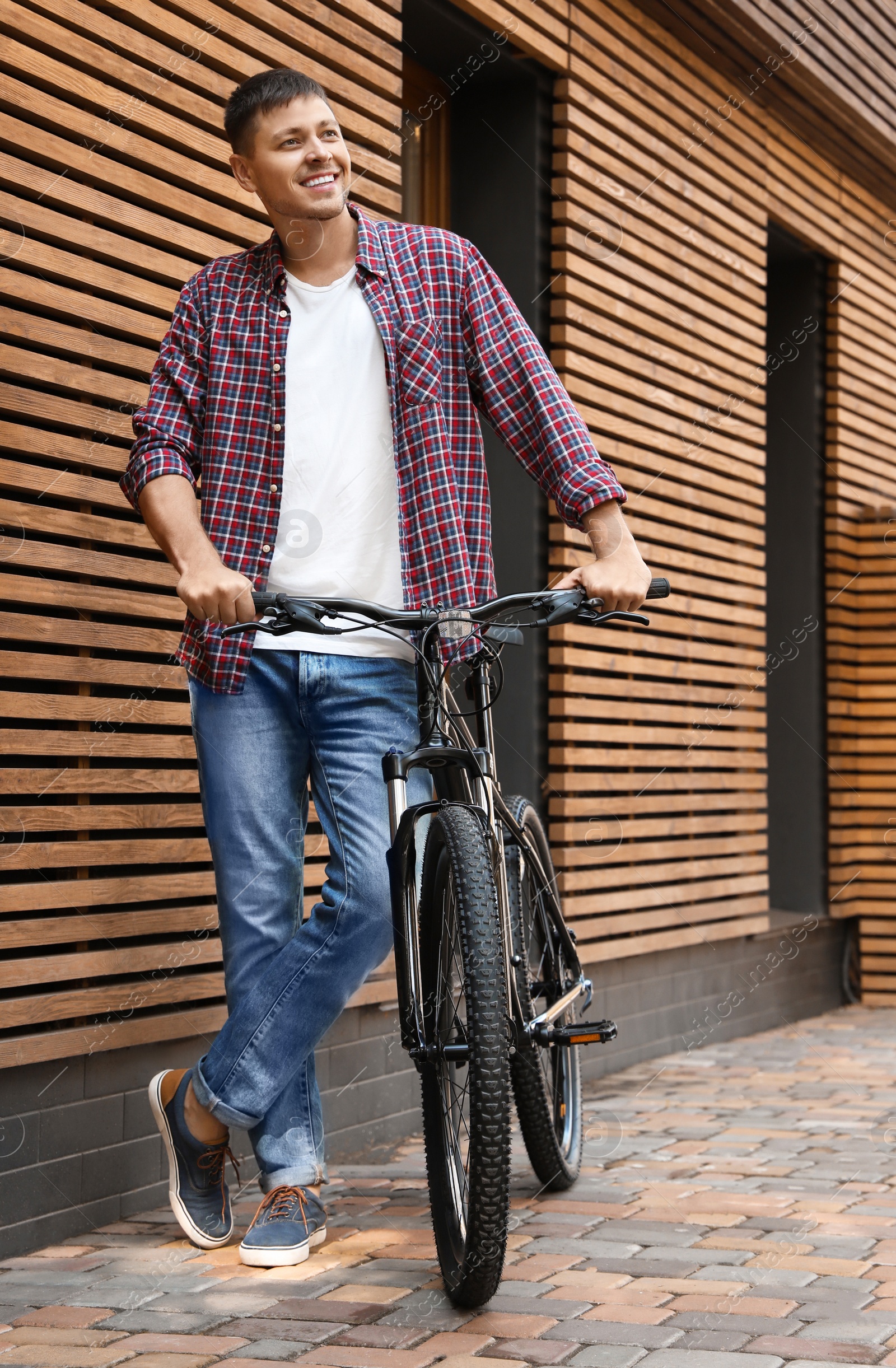 Photo of Handsome man with modern bicycle near building outdoors