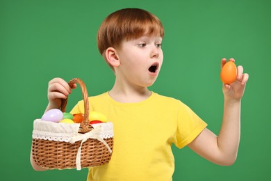 Easter celebration. Surprised little boy with painted eggs on green background