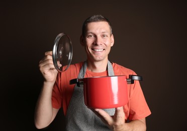Happy man with cooking pot on brown background