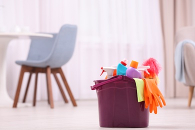 Bucket with cleaning supplies on floor indoors. Space for text