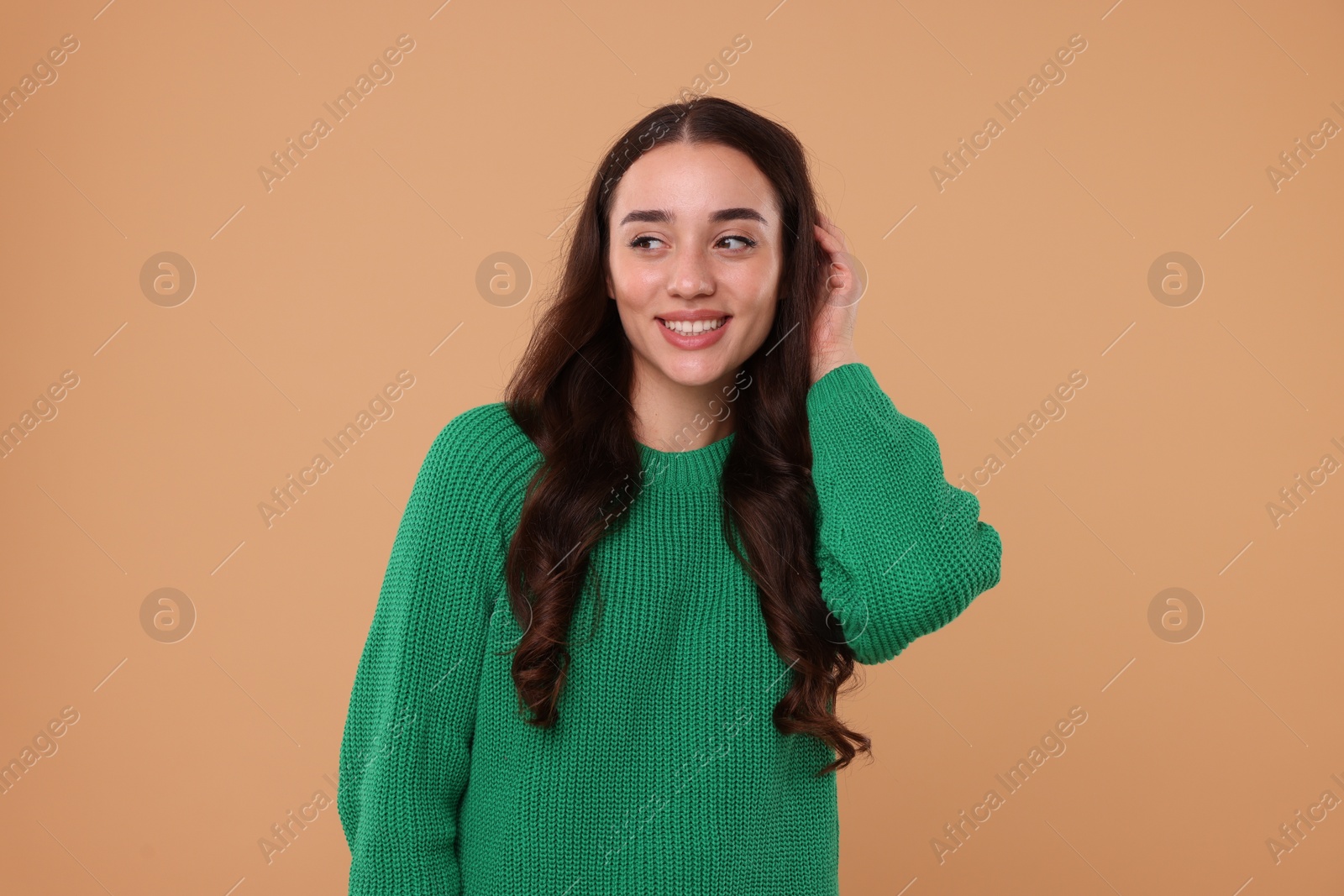 Photo of Beautiful young woman in stylish warm sweater on beige background