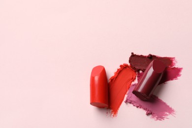 Photo of Different lipsticks and smears on light background, top view. Space for text