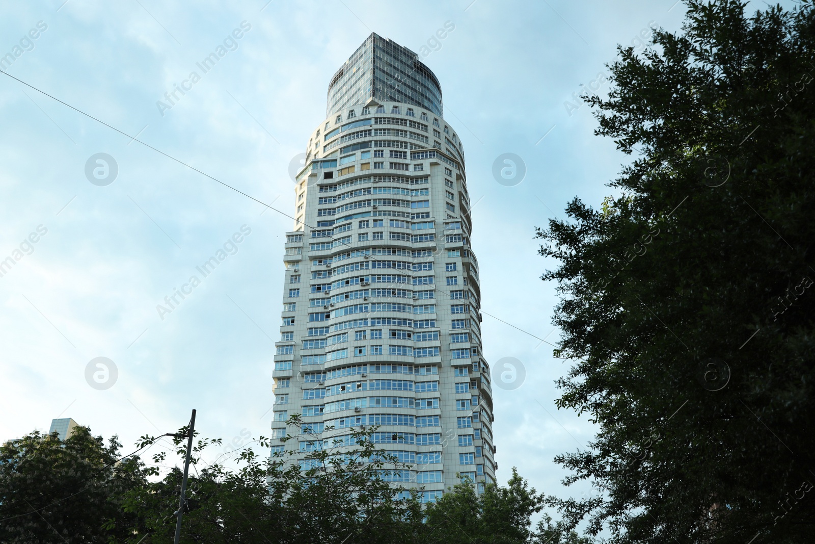 Photo of KYIV, UKRAINE - MAY 23, 2019: Modern dwelling building against sky with clouds