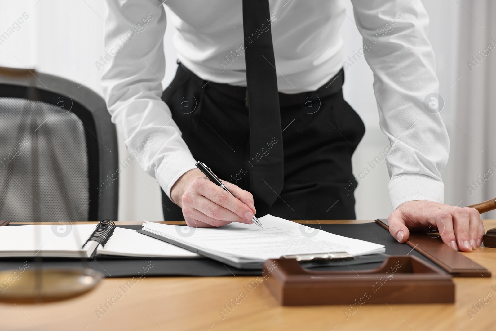 Photo of Lawyer working with documents at wooden table indoors, closeup