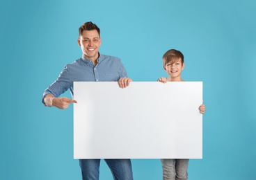 Dad and his son with empty banner on color background. Space for design