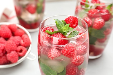 Photo of Glass of refreshing drink with raspberry and mint on grey table, closeup view