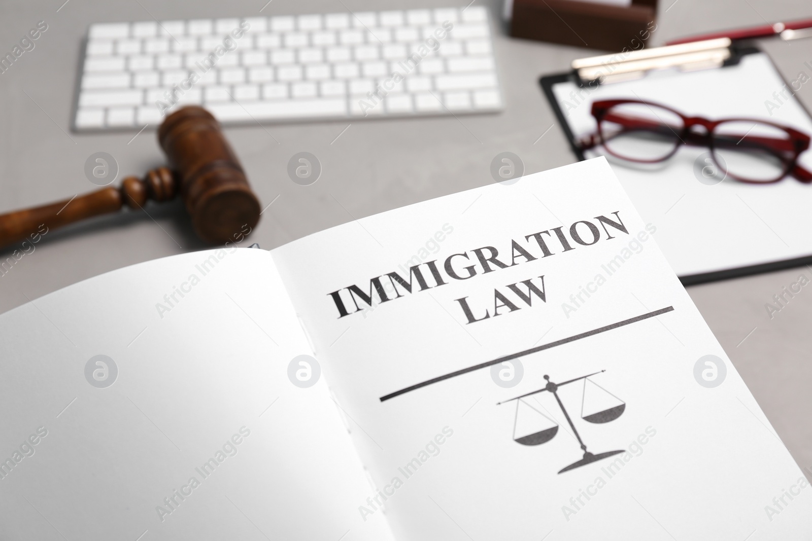 Photo of Book with words IMMIGRATION LAW, gavel and glasses on table, closeup