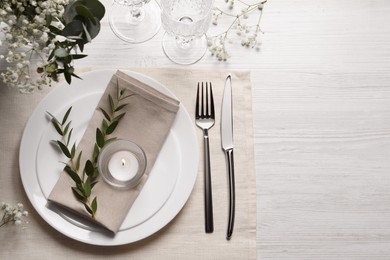Photo of Stylish setting with cutlery and eucalyptus leaves on white wooden table, flat lay. Space for text
