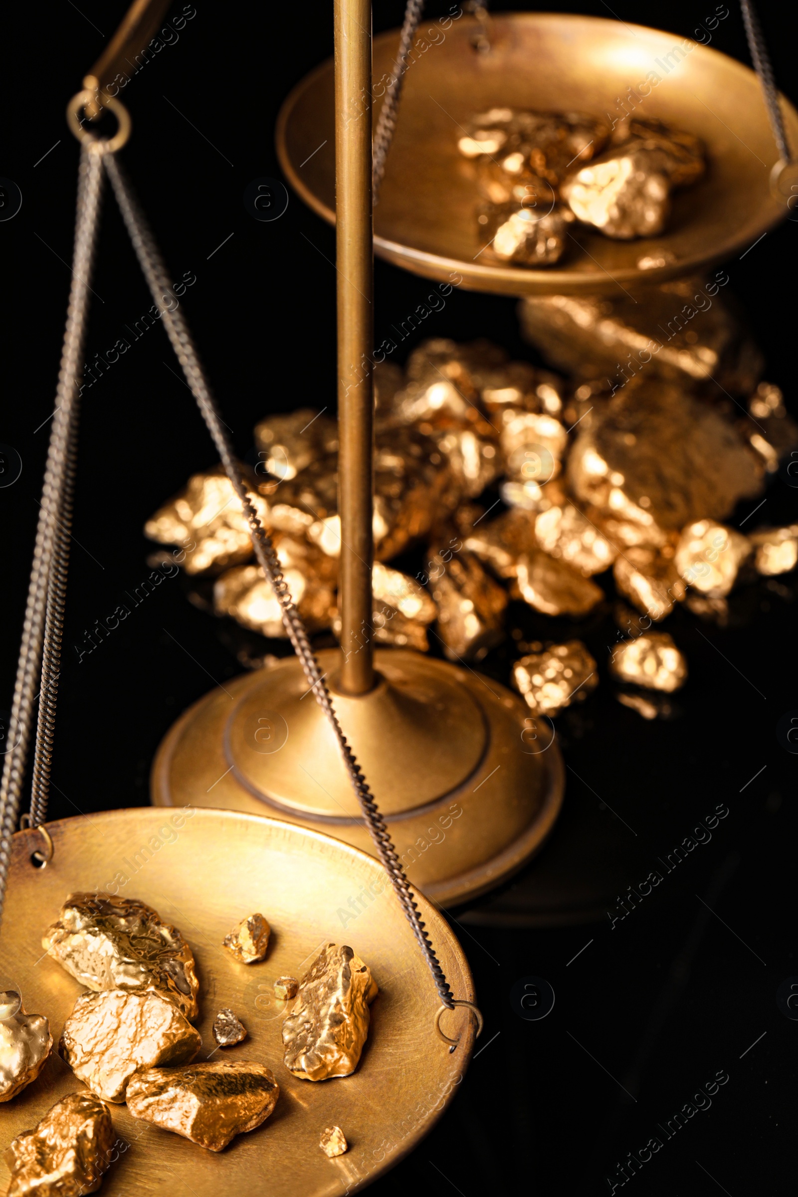 Photo of Vintage scales with gold nuggets on black background