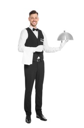 Handsome waiter holding metal tray with lid on white background