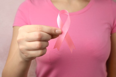 Woman holding pink ribbon, closeup. Breast cancer awareness