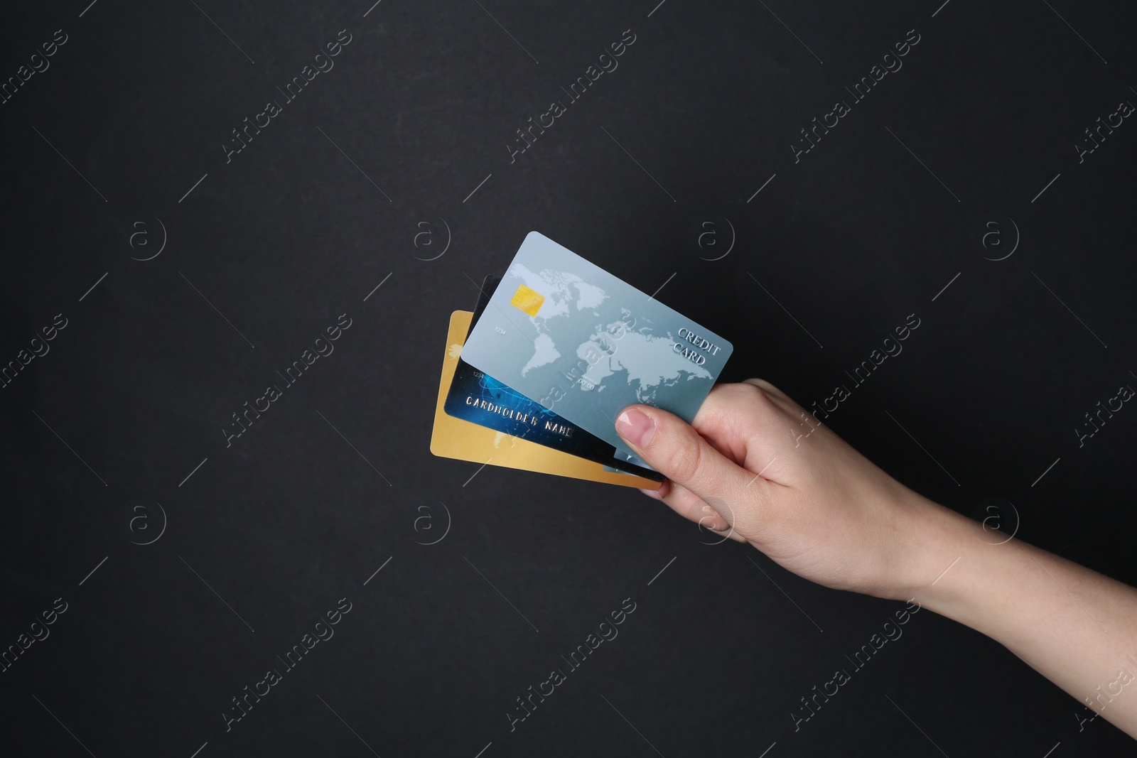 Photo of Woman holding credit cards on black background, closeup