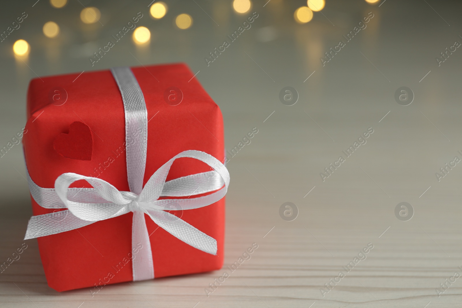 Photo of Beautiful gift box with bow on wooden table, closeup. Space for text