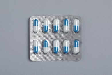 Pills in blisters on grey background, top view