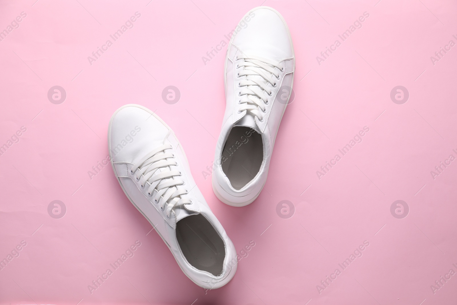 Photo of Pair of stylish white sneakers on pink background, top view