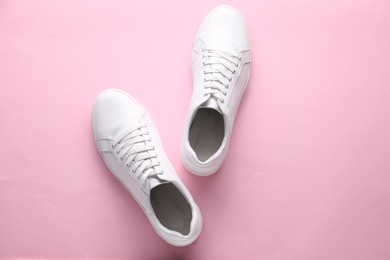 Photo of Pair of stylish white sneakers on pink background, top view